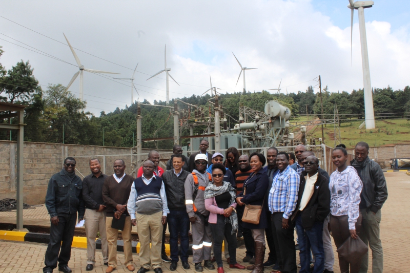 Communication experts from the RECs, Journalists, and Energy Experts in a group photo opportunity with the Electrical Engineer in charge of the Wind Farm, Eng. Kaarinah Luvango