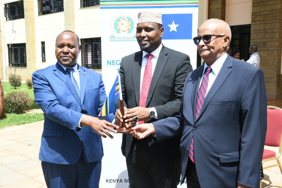 EAC Secretary General Hon. (Dr.) Peter Mathuki (left) hands over the EAC flag to the Somalia’s Minister of Planning, Hon. Mohamud Abdirahman Sheikh Farah (centre), after the official opening of the negotiations between EAC and Somalia in Nairobi. On the right is Dr. Adbusalam Omer, Special Envoy of Somalia, is the Lead Negotiator for the Federal Republic of Somalia.